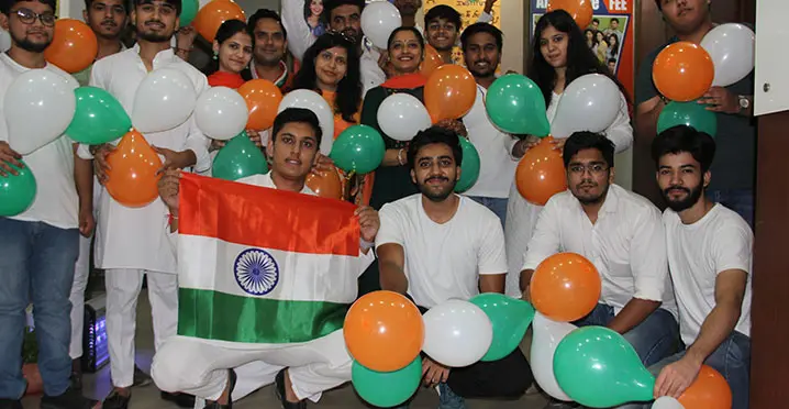 Students celebrating Independence Day with balloons and flag
